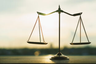 Silhouette of an empty classic balance scale against a bright sunset sky background. Symbolizes justice, equality, law, legal system, equilibrium, and ethical business choices.