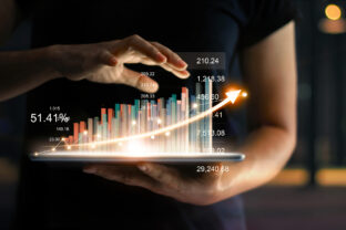 Businessman holding tablet and showing a growing virtual hologram of statistics, graph and chart with arrow up on dark background. Stock market. Business growth, planing and strategy concept.