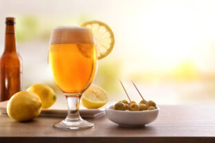 Glass of beer with lemon with appetizer on wooden table