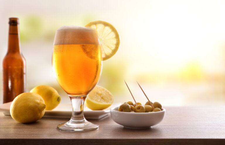 Glass of beer with lemon with appetizer on wooden table