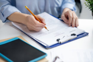 Close up of businesswoman filling tax declaration while sitting at the table