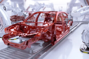 Automated car manufacturing. Industrial robotic arms painting vehicle body on a production line.