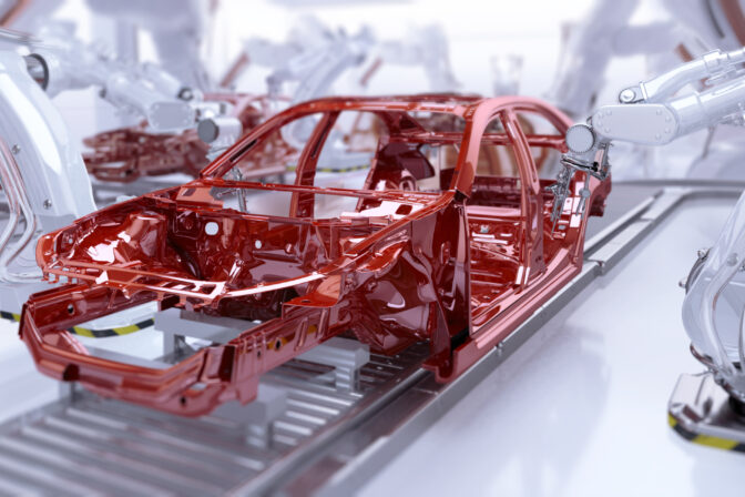 Automated car manufacturing. Industrial robotic arms painting vehicle body on a production line.