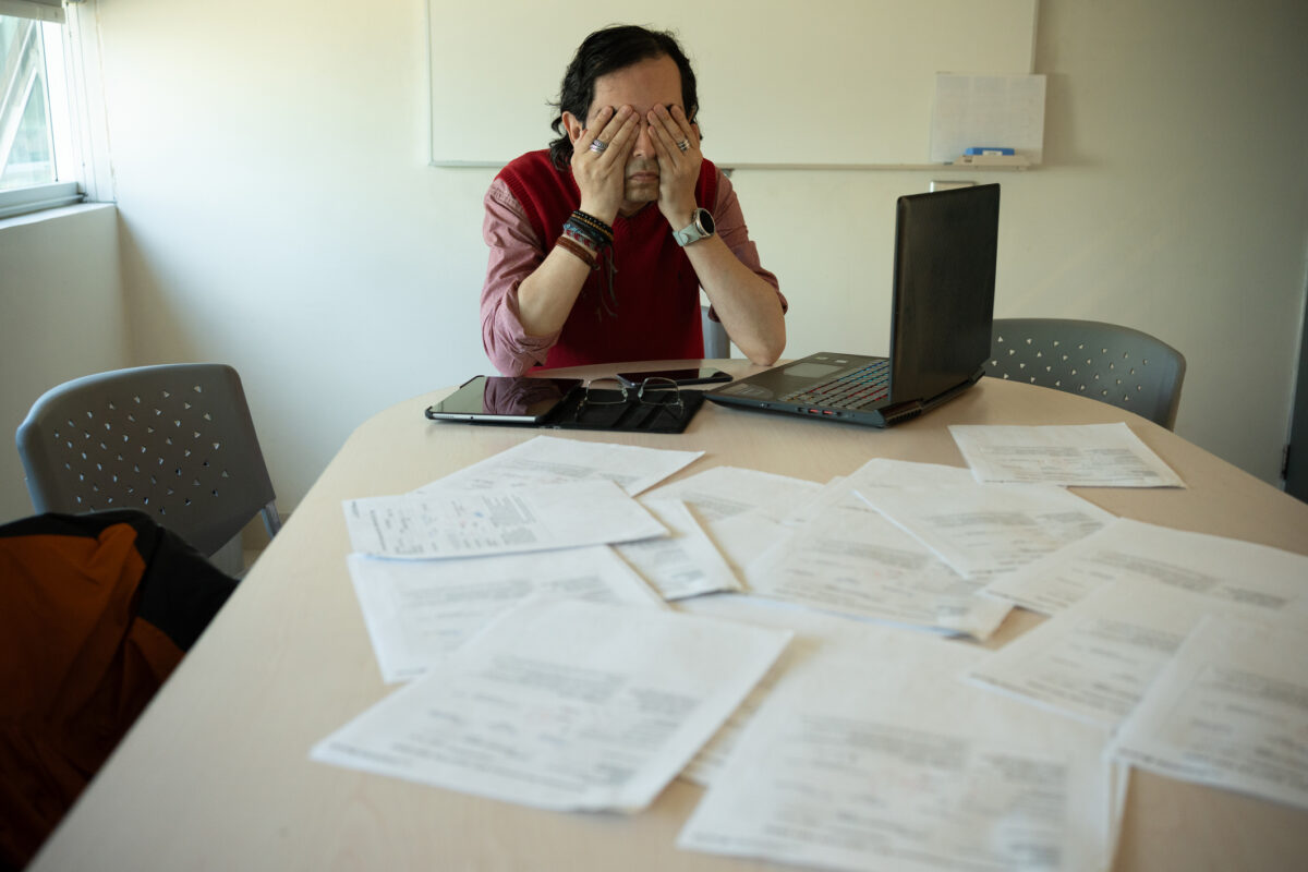 Exhausted Professor Covering Eyes Due to Workload, Tired Man Overwhelmed by Paperwork and Stress