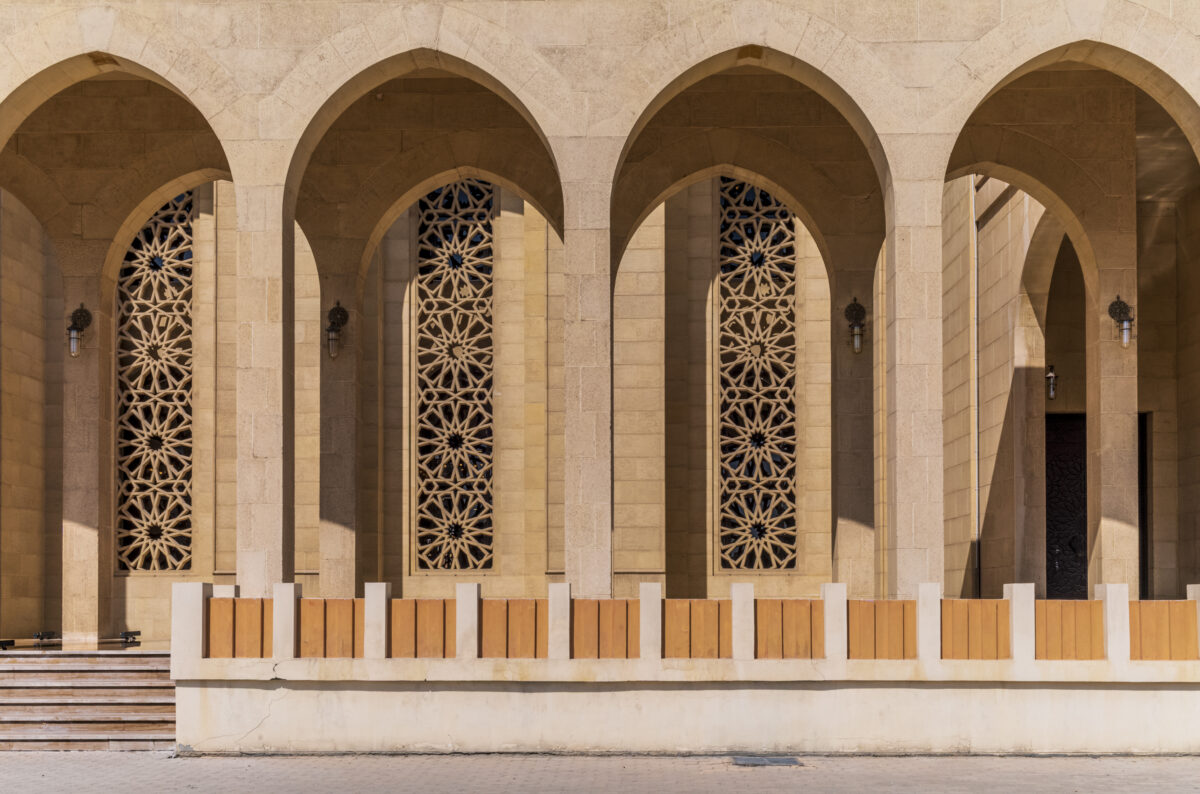 Sunlit Pointed Arches and Decorative Islamic Calligraphy at Al Fateh Grand Mosque Exterior in Bahrain