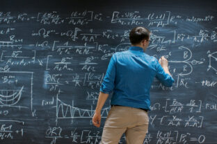 Brilliant Young Mathematician Is Writing on Big Blackboard and Thinking about Solving Long and Complex Equation/ Formula.
