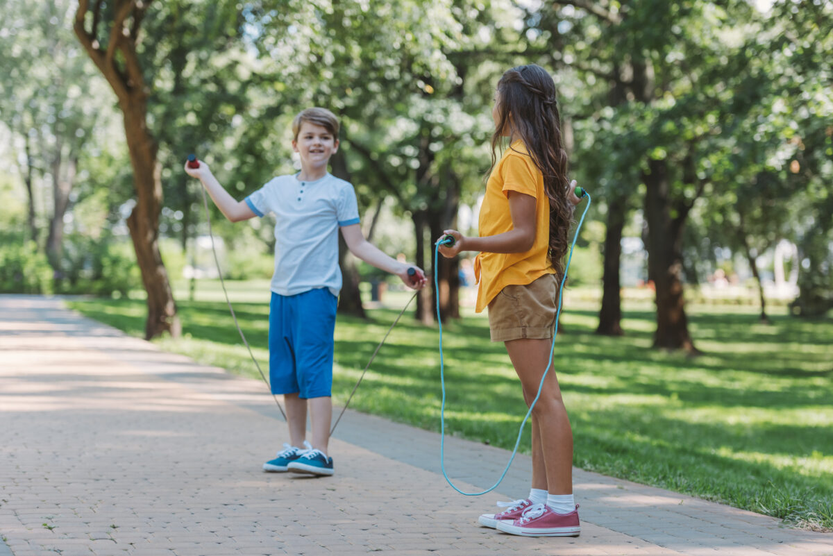 Cute happy children playing with skipping ropes in park