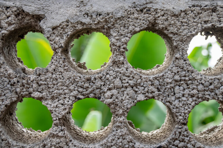Banana trees viewed through circular holes in boundary breeze concrete blocks