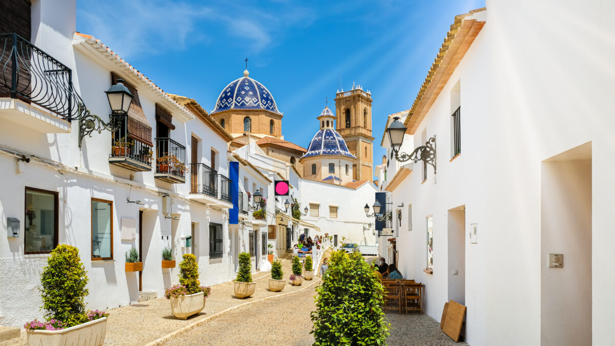 Street of Altea old town in Spain. Beautiful village with white houses and blue domed church Our Lady of Solace. Popular Spanish tourist destination, Costa Blanca region