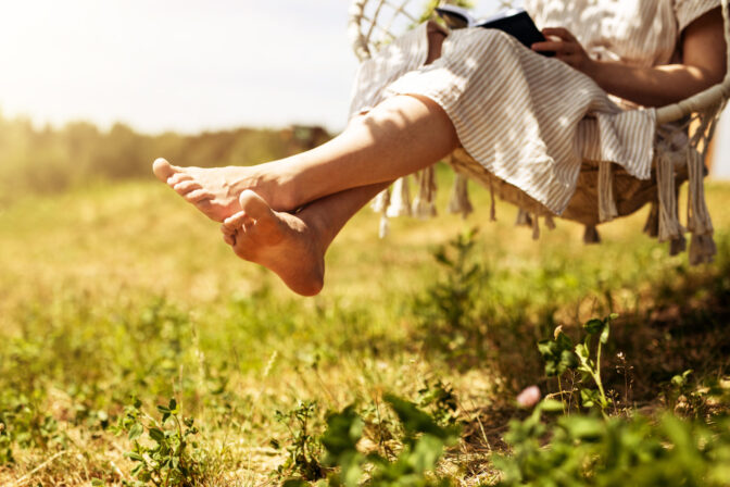 Women legs, barefoot girl sitting on swings in nature, outdoor on summer holiday