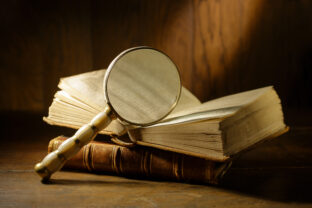 Open antique book with magnifying glass. Concept for learn history, investigation, find artifacts.