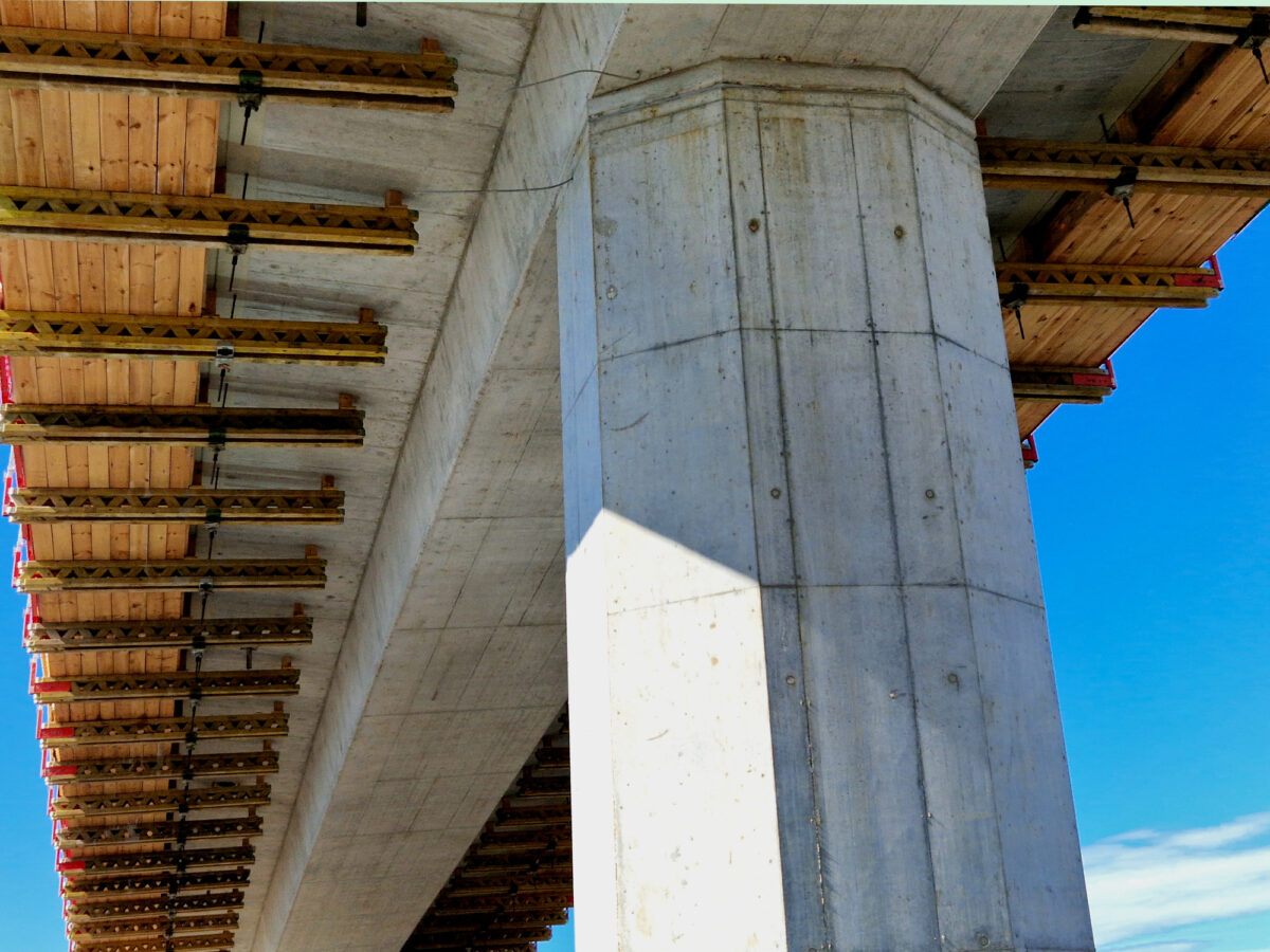 Underside of a large concrete bridge or viaduct structure under construction or heavy maintenance.