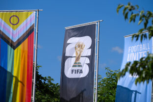 Flags waving at entrance of FIFA Headquarters with world cup 2026 logo on a sunny day.
