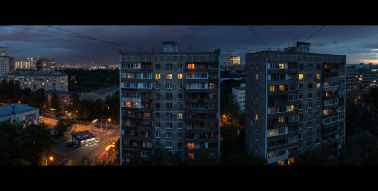 Architecture of the Soviet Union. Two tall houses on the street on March 8. View from the apartment window. Evening city after the rain. Lights up in the Windows