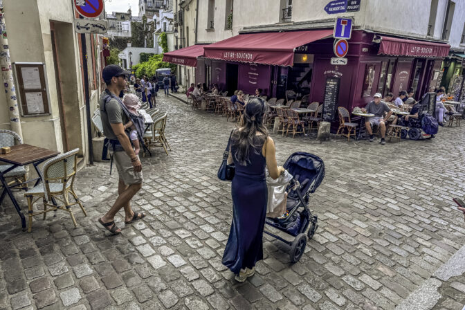 Young Parents Carrying Baby Stroll Through Rue Poulbot in Montmartre Paris France