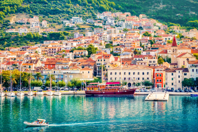 Aerial view Colorful waterfront of Makarska on the Adriatic Sea, Croatia. Sailboats and a red yacht in the marina below Biokovo mountainsâsunny summer travel destination.