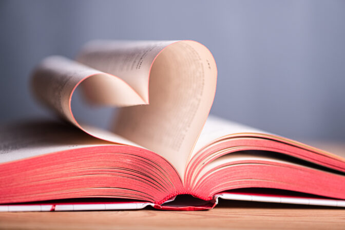 Open book forms heart shape with pages, showcasing love for reading and knowledge in a simple educational setting filled with literature