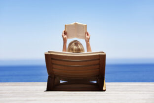 Rear view of woman reading outdoors in wooden chair
