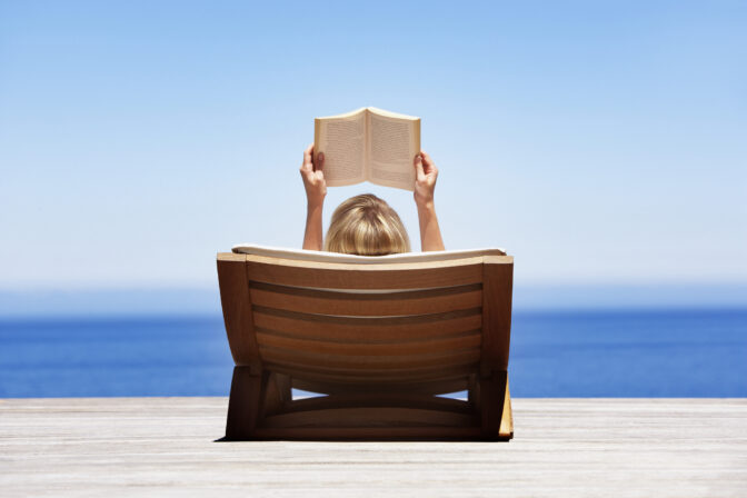 Rear view of woman reading outdoors in wooden chair