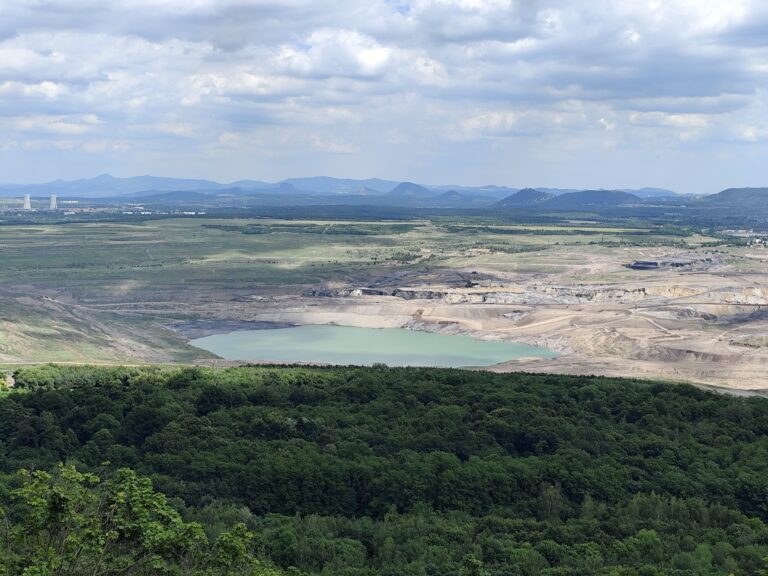 Panoráma z terasy zámku Jezeří patrí k najsilnejším zážitkom celej návštevy. Na mieste niekdajších dedín, jazera a rozsiahlych parkov sa dnes rozprestiera povrchový hnedouhoľný lom, ktorý je symbolom dramatickej premeny severočeskej krajiny.