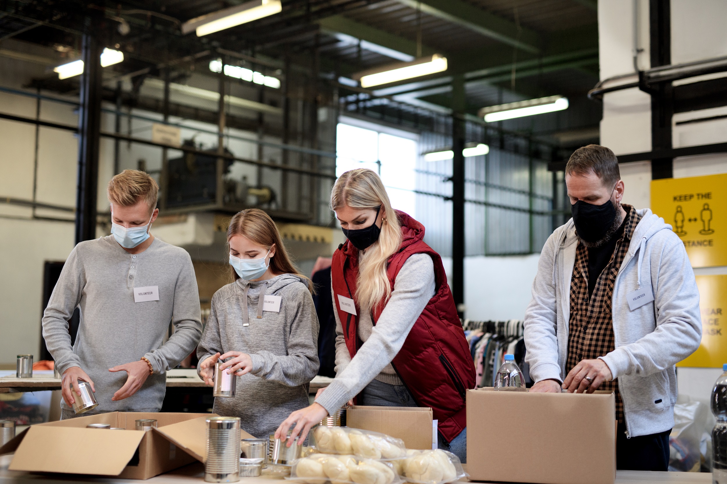 Group of volunteers in community charity donation center, food bank and coronavirus concept.