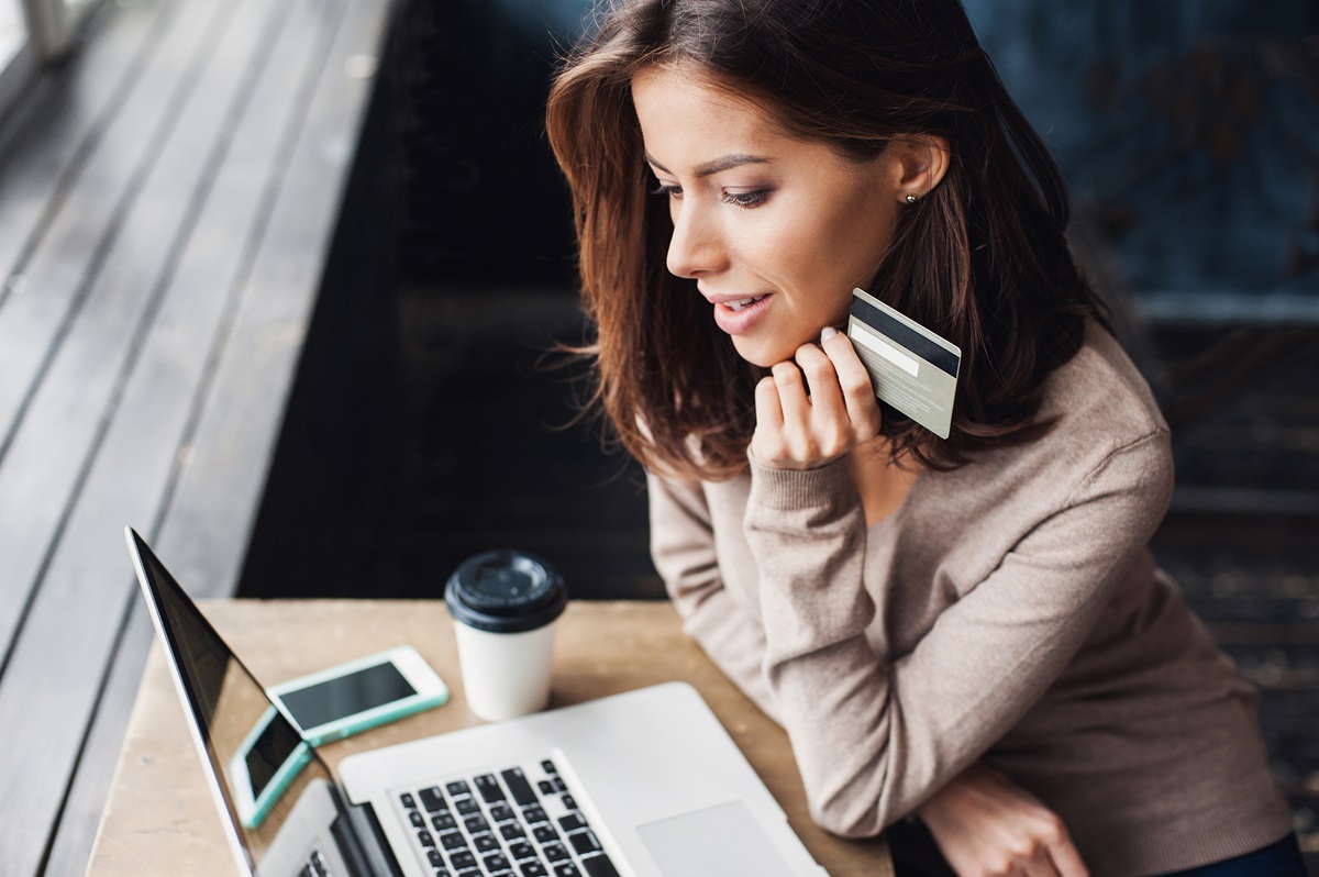 Young woman holding credit card and using laptop computer. Onlin