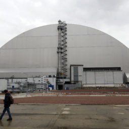 FILE - A man walks past a shelter covering the exploded reactor at the Chernobyl nuclear plant, in Chernobyl, Ukraine, Thursday, April 15, 2021. When fighting from Russia’s invasion of Ukraine resulted in power cuts to the critical cooling system at the closed Chernobyl nuclear power plant, some feared that spent nuclear fuel would overheat. But nuclear experts say there’s no imminent danger because time and physics are on safety's side