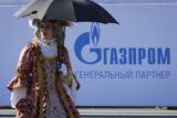 An actor wearing XVIII century dress walks past a logo of Russian gas monopoly Gazprom in St. Petersburg