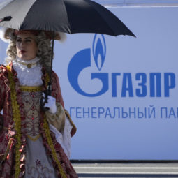 An actor wearing XVIII century dress walks past a logo of Russian gas monopoly Gazprom in St. Petersburg