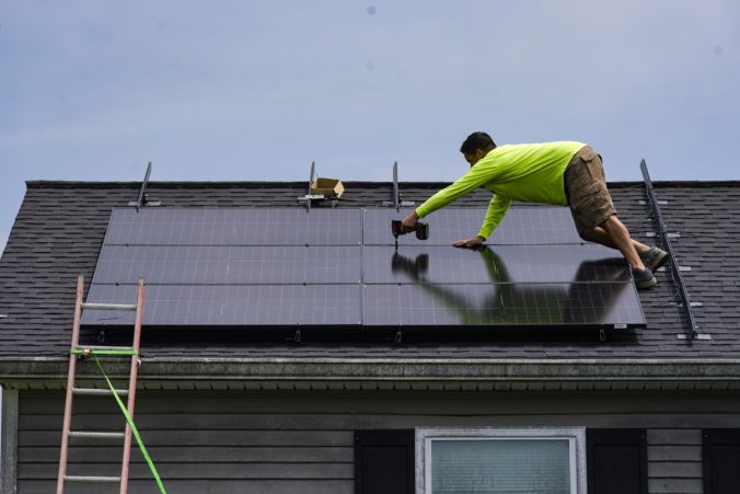 Nicholas Hartnett, owner of Pure Power Solar, secures solar panel on the roof of a home in Frankfort, Ky., Monday, July 17, 2023. Since passage of the Inflation Reduction Act, it has boosted the U.S. transition to renewable energy, accelerated green domestic manufacturing, and made it more affordable for consumers to make climate-friendly purchases, such as installing solar panels on their roofs