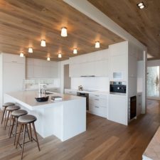 Post_wood ceiling with contemporary lighting fixtures and glossy white kitchen island and industrial stools.jpg