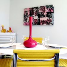 Post_yellow themed dining room with unique patterned chair facing white round table beneath pink porcelain.jpg