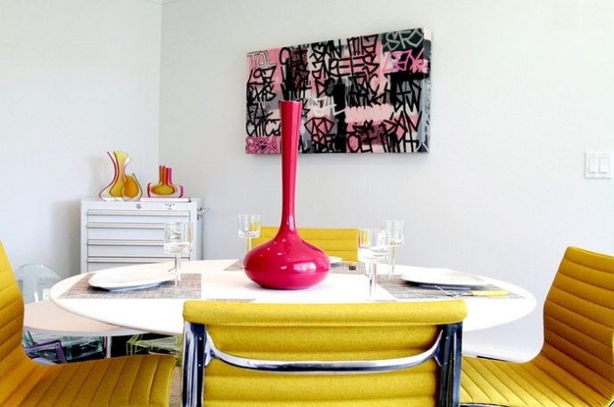 Post_yellow themed dining room with unique patterned chair facing white round table beneath pink porcelain.jpg