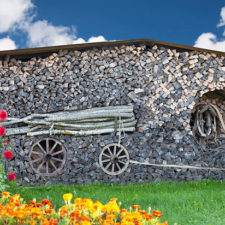 Stacked firewood art. Piled wood, grass and flowers.