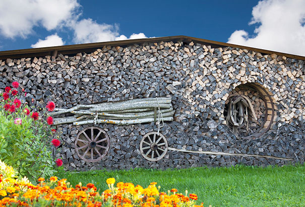 Stacked firewood art. Piled wood, grass and flowers.