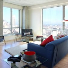 Post_studio apartment interior design blue sofas white wall twin glasses table white furry rug glasses wall white ceiling red stand lamp red pillows wooden floor painting black chair black armchair whi.jpg