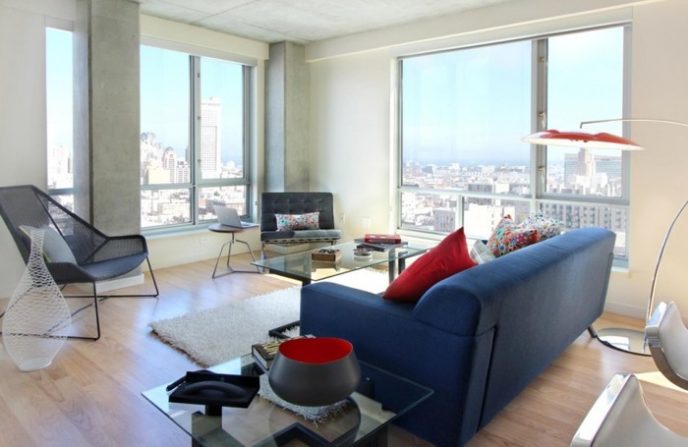 Post_studio apartment interior design blue sofas white wall twin glasses table white furry rug glasses wall white ceiling red stand lamp red pillows wooden floor painting black chair black armchair whi.jpg