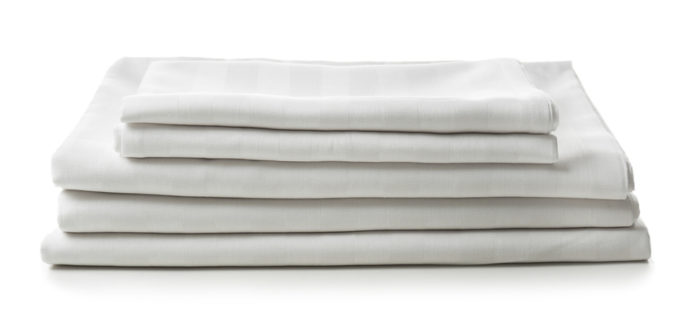 Stack of clean bed sheets on white background