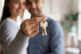 Close up happy young woman hugging man, holding keys