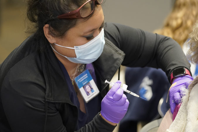 Katherine Thompson, an emergency medical technician working as a contractor with the Federal Emergency Management Agency, gives a person a Pfizer COVID-19 vaccine booster shot, Monday, Dec. 20, 2021, on the first day of a COVID-19 vaccination clinic in Federal Way, Wash. The clinic is operated by King County Public Health and other partners with support from FEMA staff and contract workers, who have been traveling across the U.S. to set up temporary community vaccination centers, including in some areas with mobile bus-based clinics, in efforts to increase the availability of COVID-19 vaccinations and booster shots. ()