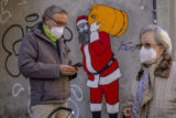 Virus Outbreak Spain FILE - A man and woman wearing FFP2 masks to curb the spread of COVID 19 are seen in front of a mural depicting Santa Claus, in Madrid, Spain, on Jan. 12, 2022. Spain will end a mandate to wear masks outdoors next week, reverting a late December order against an unprecedented surge of coronavirus infections fueled by a highly contagious mutation.