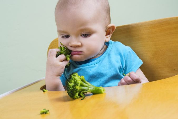 Funny baby eating broccoli